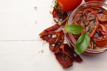 Glass jar with sun dried tomatoes on wooden table