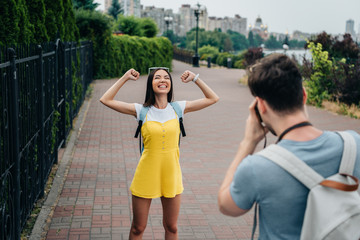 man taking photo and asian woman showing yes gesture