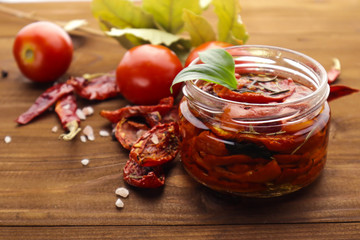 Glass jar with sun dried tomatoes on wooden table
