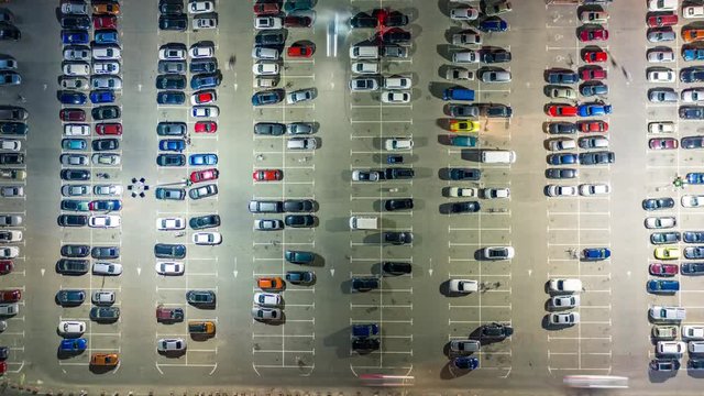 Aerial top view of the supermarket (hypermarket or shopping mall) parking lot with lots of cars at night. Time lapseg lot with lots of cars at night. Time lapse