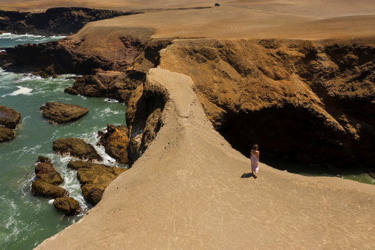 Aerial view of woman taking a view in a shore cliff in Huarmey, Ancash region in Peru