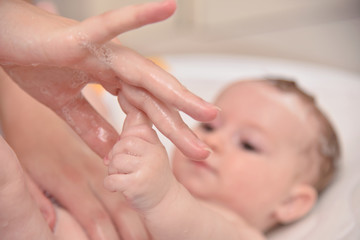 Pretty three months baby girl taking a bath by her mother at home, european child.