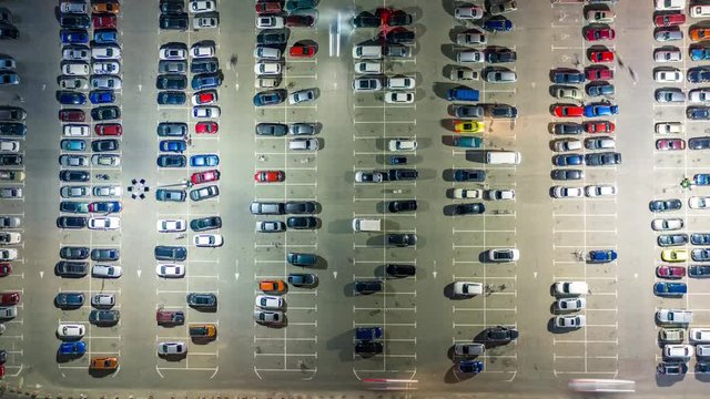 Aerial top view of the supermarket (hypermarket or shopping mall) parking lot with lots of cars at night. Time lapse