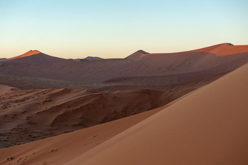 Fototapeta na wymiar Early morning sunlight illuminating the red sand of Namibias sussusvlei