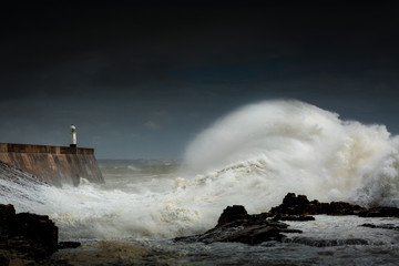 Fototapeta na wymiar Porthcawl lighthouse and pier in the jaws of a storm on the coast of South Wales, UK.