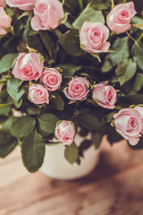 Gorgeous bouquet of flowers in a white pot. Pink and raspberry roses in a vase on the window.