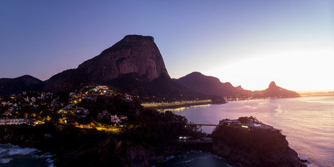 Aerial view of Joatinga beach with the Gavea, Vidigal and Corcovado mountains in the background and Costa Brava club in the foreground at dawn with street lights on and intense early morning colours