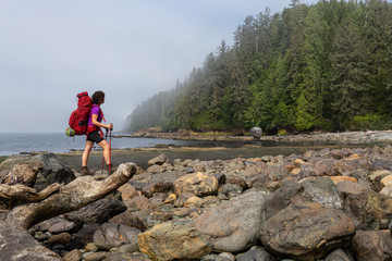 Adventurous girl hiking Juan de Fuca Trail to Bear Beach on the Pacific Ocean Coast during a sunny and foggy summer morning. Taken near Port Renfrew, Vancouver Island, BC, Canada.