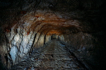 Dark dirty abandoned uranium mine with rusty remnants of railway