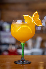 Orange tonic cocktail, with ice on a bar background.