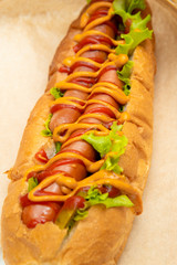 Hot dog with salad and cucumbers with tomato ketchup and mustard on white background. Tasty and beautiful fast food on a light back.