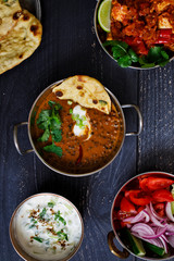 Indian curry meal with black lentils dal, spicy potatoes, rice, naan bread and raita