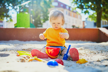 little girl having fun on playground in sandpit