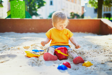 little girl having fun on playground in sandpit