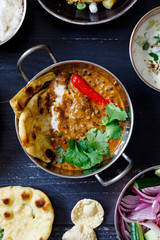 Indian curry meal with black lentils dal, salad, naan bread and raita