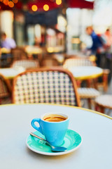 Cup of fresh hot espresso coffee on table of traditional Parisian outdoor cafe in Paris