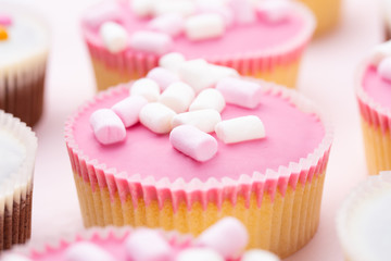 Colorful cupcakes on a pink background.