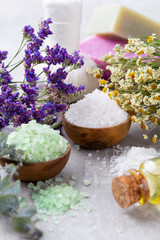 Sea salt in bowl, aroma oil in bottles, Wellness and flowers on grey textured background and flowers on vintage wooden background. Selective focus.