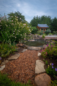 Pagoda and Pond on a Misty Morning with Hibiscus Flower Bush and Stone Lined Walking Path