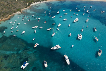 Fototapeta na wymiar View from above, stunning aerial view of a beautiful bay full of boats and luxury yachts. A turquoise sea bathes the green and rocky coasts. Liscia Ruja, Emerald Coast (Costa Smeralda) Sardinia, Italy