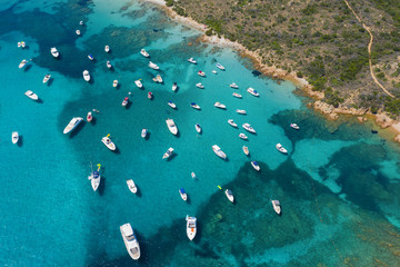 View from above, stunning aerial view of a beautiful bay full of boats and luxury yachts. A turquoise sea bathes the green and rocky coasts. Liscia Ruja, Emerald Coast (Costa Smeralda) Sardinia, Italy