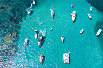 View from above, stunning aerial view of a beautiful bay with turquoise water full of boats and luxury yachts. Liscia Ruja, Emerald Coast Sardinia, Italy.