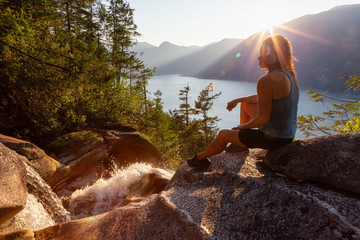 Adventurous Girl is sitting on top of a Beautiful Waterfall, Shannon Falls, and watching the...