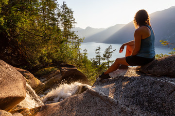 Adventurous Girl is sitting on top of a Beautiful Waterfall, Shannon Falls, and watching the...