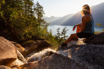 Adventurous Girl is sitting on top of a Beautiful Waterfall, Shannon Falls, and watching the...