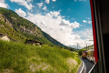 View from train riding through the Swiss Alps. Red panoramic train