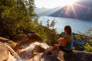 Adventurous Girl is sitting on top of a Beautiful Waterfall, Shannon Falls, and watching the...
