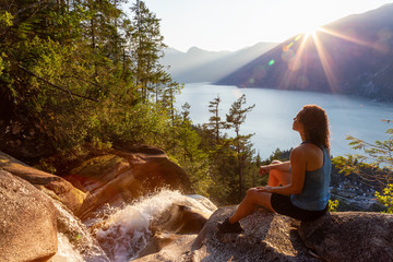 Adventurous Girl is sitting on top of a Beautiful Waterfall, Shannon Falls, and watching the...