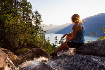 Adventurous Girl is sitting on top of a Beautiful Waterfall, Shannon Falls, and watching the...