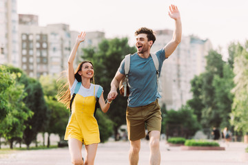 Obraz premium handsome man and asian woman running and waving outside