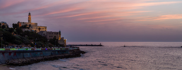 Beautiful panoramic view of a beach in the Old Port of Jaffa during a sunny and colorful sunset. Taken in Tel Aviv, Israel.