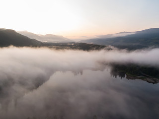 Fototapeta premium Aerial Panoramic View of Fairy Lake covered in clouds during a vibrant summer sunrise. Taken near Port Renfrew, Vancouver Island, British Columbia, Canada.