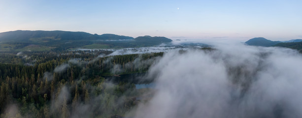 Aerial Panoramic View of Fairy Lake covered in clouds during a vibrant summer sunrise. Taken near Port Renfrew, Vancouver Island, British Columbia, Canada.