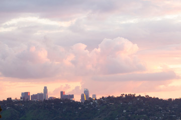hillside view of homes with downtown towers under baby pink, lavender and blue sunset