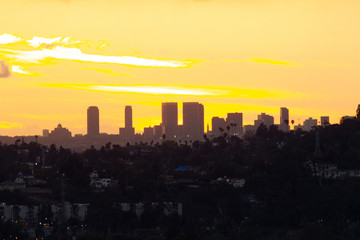 Fototapeta na wymiar distant downtown towers in sunset glow with panoramic view of yellow sunrays on red glow