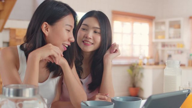 Asian Lesbian lgbtq influencer women couple vlog at home, Young Asia girls happy using tablet vlog video in social media show wedding rings while have breakfast in kitchen in the morning concept.