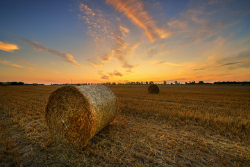 Beautiful summer sunset over fields with hay bales