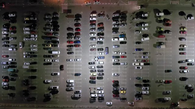 Aerial top view of the supermarket (hypermarket or shopping mall) parking lot with lots of cars at night