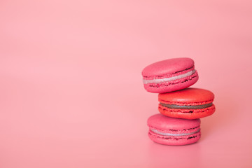 Red and pink macaroons on coral background, home-made food