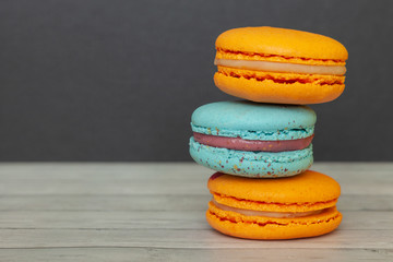 Orange and blue macaroons on a dark background, French cookies as a treat for the holiday