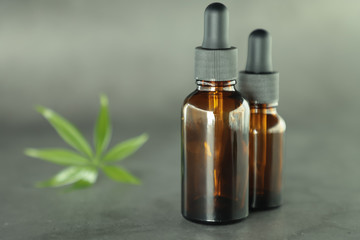 Dark glass bottles with full, cannabidiol oil and hemp leaves on a pastel background. Health conception. Medical marijuana.