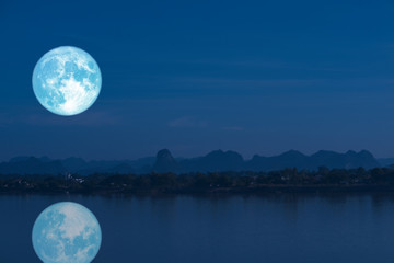 Fototapeta na wymiar full milk moon back on silhouette mountain and reflection on river night sky