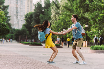 handsome man and woman smiling, jumping and holding hands