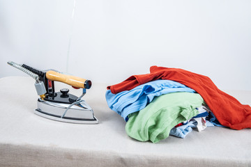 A pile of clothes and irons that need to be ironed on the table