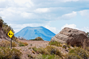 Landslide sign on dirt road with a Volcano background
