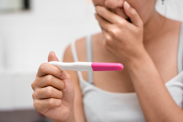 Young asian woman holding pregnancy test and shocked with result in her bathroom, wellness and...